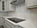 Close-up of the kitchen with a modern cooktop and elegant marble tile backsplash at 145 Green Haven Blvd # 83, Youngsville, NC 27596