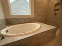 Large soaking tub surrounded by tile with a view to the outside at 145 Green Haven Blvd # 83, Youngsville, NC 27596