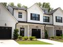 Beautiful townhome featuring stone accents, black shutters, dark roofing, and a lush green lawn at 727 Putney Hill Rd, Zebulon, NC 27597