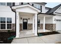 A covered front porch features white columns, brick accents, and a black front door at 490 Oak Park Blvd, Youngsville, NC 27596