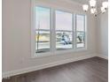 Well-lit dining room showcasing hardwood floors, large windows, and a modern chandelier at 524 Lemon Daisy Ln, Knightdale, NC 27545