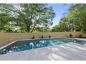 Beautiful backyard pool with light stone tiling and privacy fencing surrounded by trees at 712 Daniels St, Raleigh, NC 27605