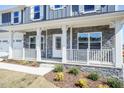 Inviting front porch with white railings and stone accents on a new home at 525 Glenkirk Pl, Garner, NC 27529