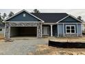 New construction home features blue siding, stone accents and a two-car garage in a residential neighborhood at 55 Streamline Ct, Lillington, NC 27546