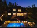 Back exterior view with a large pool, lighted stairs, deck and patio at 60 Citori Ct, Pittsboro, NC 27312