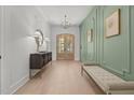 Elegant entryway with light wood floors, decorative wall paneling, a stylish console table, and an arched front door at 701 Dartmouth Rd, Raleigh, NC 27609