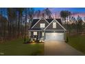 Charming home featuring a two-car garage, covered porch and craftsman details at twilight at 145 Leisure Ln, Louisburg, NC 27549