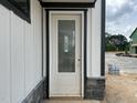 Entry door with glass and white trim surrounded by stone and white siding at 2400 Adrift Rd, Fuquay Varina, NC 27526