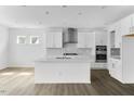 Modern white kitchen features an island with seating, stainless steel appliances, and sleek countertops at 929 Kinglet House Rd, Knightdale, NC 27545