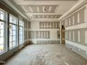 Bright, unfinished living room featuring trim work on the ceiling and three large windows at 7000 North Ridge Dr, Raleigh, NC 27615