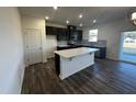 Modern kitchen with dark cabinets, island, and hardwood floors at 566 John Stark Dr, Fuquay Varina, NC 27526