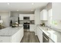 Modern kitchen with stainless steel appliances, granite countertops, white cabinets, and an island with barstool seating at 1585 Ivy Meadow Ln, Zebulon, NC 27597
