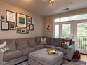 Comfortable living room with a large gray sectional, ottoman, and access to a balcony at 1001 Hillsborough St # 304, Raleigh, NC 27603