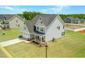 Aerial view of a light blue two-story home with attached garage, green lawn, and neighborhood view at 443 Ravensworth Dr, Garner, NC 27529