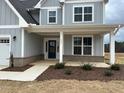 Home's entryway showcases a charming front porch with brick accents and a neatly landscaped yard at 443 Ravensworth Dr, Garner, NC 27529