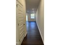 Inviting hallway with hardwood floors, neutral paint and recessed lighting leading to a window and outdoor patio at 1050 Mountain Crown St, Durham, NC 27703