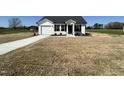 A single-story home features a driveway leading to an attached garage, surrounded by a spacious green space at 111 Johnson Ridge Way, Four Oaks, NC 27524
