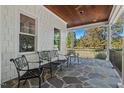 View of a relaxing covered patio with stone floor, wooden ceiling, and wrought iron furniture at 488 Colvard Farms Rd, Durham, NC 27713