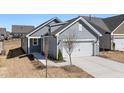 Attractive exterior showcasing a gray home with a spacious two-car white garage, set against a landscaped yard at 1829 Hydrangea Way, Fuquay Varina, NC 27526