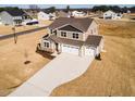Aerial view of a two-story home with a three-car garage, spacious yard, and beige siding and dark brown roof at 224 Bering Cir, Angier, NC 27501