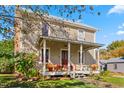 Charming two-story home with a covered front porch, landscaping, and seasonal flowers at 2416 Glencoe St, Burlington, NC 27217