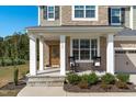 Inviting front porch with stone flooring, rocking chairs, and a wooden front door at 120 W Weatherford Dr, Angier, NC 27501