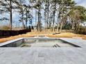 Unfinished outdoor pool and spa with tile surround and wooded view, perfect for relaxation and entertaining at 662 Manchester Dr, Raleigh, NC 27609