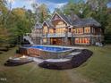 Luxurious backyard featuring a sparkling pool, a fire pit, and a beautifully designed stone patio with outdoor seating at 3105 Cone Manor Ln, Raleigh, NC 27613