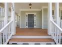 Inviting front porch with wood flooring, white columns, and a view of the front yard at 2024 Stanchion St, Haw River, NC 27258