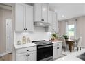 Modern kitchen featuring white cabinets, stainless steel appliances, tile backsplash and view to the eat-in kitchen at 8841 Tartan Clan Dr, Willow Springs, NC 27592