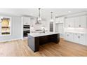 Spacious kitchen with white cabinets, a stainless hood, an island and hardwood floors at 55 Firefly Ln, Louisburg, NC 27549