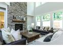 Cozy living room featuring stone fireplace, large windows, and stylish furniture at 274 Golden Leaf Farms Rd, Angier, NC 27501