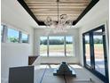 Dining area featuring a modern chandelier, large windows with scenic view, and dark framed glass doors at 280 Forest Bridge Rd, Franklinton, NC 27525