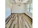 Dining room with wainscoting, a modern chandelier, wood-look floors, and bright natural light at 40 Sunrise Ct, Spring Hope, NC 27882