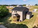 Back view of tan home with a screened in porch and large backyard in new development at 240 Fast Pitch Ln, Four Oaks, NC 27524