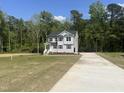 Two-story home with gray siding, an inviting front porch, a long driveway, and a spacious front yard at 266 Fast Pitch Ln, Four Oaks, NC 27524