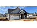 A charming new home with a brick facade, gray siding, and a well-manicured lawn under a partly cloudy sky at 1044 Fairhaven Dr # 100, Mebane, NC 27302