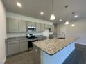 Open kitchen with a large granite island, modern lighting, stainless steel appliances, and gray cabinets at 346 Olivia Crossing Ct # 12, Four Oaks, NC 27524