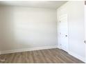 Bright, empty bedroom featuring hardwood floors, neutral walls, and a door, ready for customization at 490 Barbour Farm Ln, Four Oaks, NC 27524