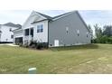 Beautiful exterior featuring gray siding, white trim, and a well-maintained lawn on a sunny day at 490 Barbour Farm Ln, Four Oaks, NC 27524