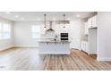 Bright, open kitchen with a center island, modern stainless steel appliances, and wood-look flooring at 490 Barbour Farm Ln, Four Oaks, NC 27524