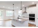 Modern kitchen with granite countertops, sleek black faucet, stainless appliances, and wood-look flooring at 490 Barbour Farm Ln, Four Oaks, NC 27524