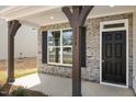 Inviting front porch with stone accents, timber supports, and a stylish black front door at 1228 Cricket St, Elon, NC 27244