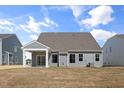 Rear view of the house with a covered patio, grassy yard, and neutral-colored siding at 1232 Cricket St, Elon, NC 27244