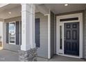 Close up of the front door and porch showcasing gray siding and a stone accent wall at 1232 Cricket St, Elon, NC 27244