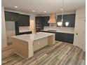 Open kitchen showcasing a large center island with a white countertop, custom cabinets, and hardwood floors at 684 Magnolia Acres Ln, Fuquay Varina, NC 27526