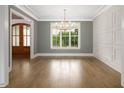 Bright dining room with a stylish chandelier, decorative wall paneling, and hardwood floors at 70 Water Willow Ln, Zebulon, NC 27597