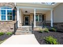 Inviting front porch with stone steps, black railings, and stylish landscaping at 160 Purslane Dr, Franklinton, NC 27525