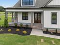 Close-up of the home's entrance, featuring a brick-accented porch and a beautiful wood and glass front door at 5124 Grist Stone Way, Youngsville, NC 27596