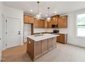 A modern kitchen featuring wood cabinets, quartz countertops, stainless steel appliances, and stylish pendant lighting at 810 Barlow Dr, Knightdale, NC 27545